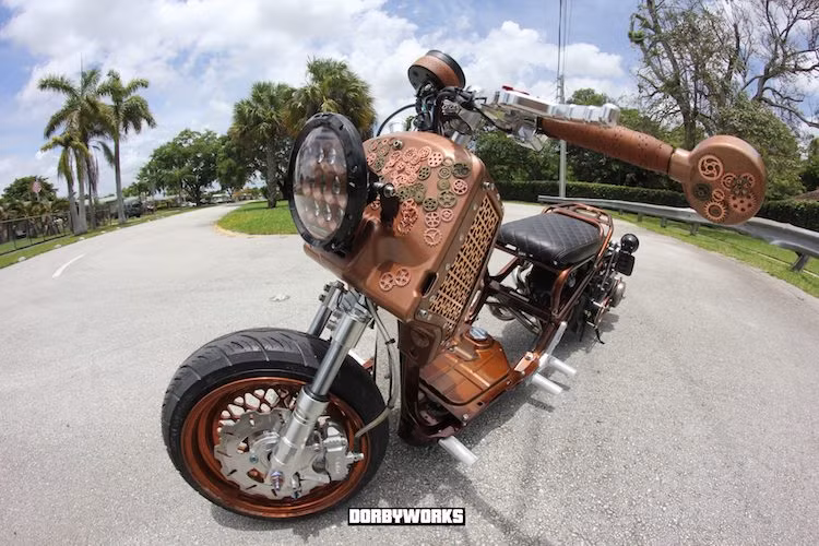 Hệ thống phanh trước là loại 4 piston của RRGS. Theo phong cách steampunk, phần hộp nhựa phía trước xe đã được trang trí bằng hàng trăm bánh răng của đồng hồ, cùng với 2 cạnh bên làm từ lưới đồng CNC hình hoa văn đẹp mắt. Tay lái nguyên bản của chiếc xe cũng được thay bằng cặp ghi-đông clip-on với bao tay là những dải da cuốn cổ điển.