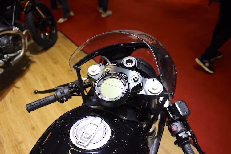 Theo phong cách cafe racer, ghi-đông nguyên bản của chiếc Scrambler Sixty2 đã được thay bằng cặp tay lái clip-on đặt cực thấp, tạo tư thế ngồi thể thao. Cụm đồng hồ tròn nguyên bản đặt lệch phía trên chảng ba đã được Sang Thanh Đa "di dời" ra vị trí trung tâm bằng pad nhôm CNC bắt vào vị trí ốc gù ghi-đông nguyên bản.