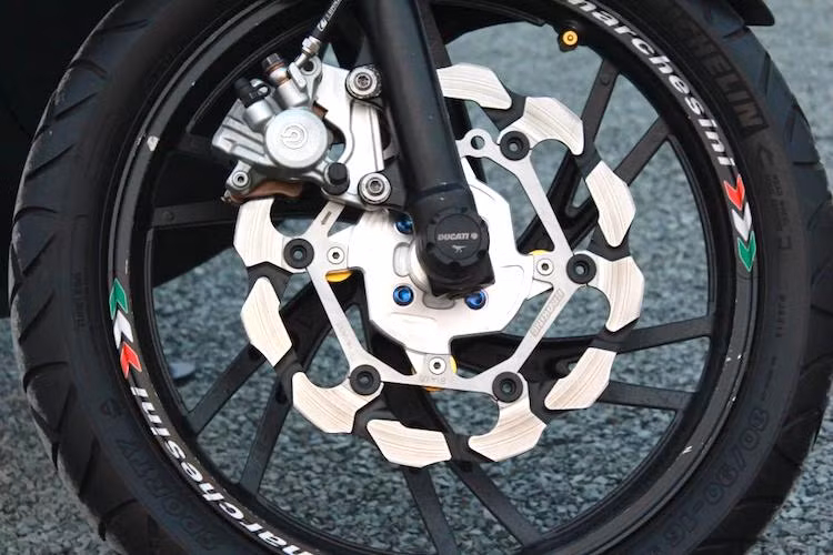 Ở phía trước, hệ thống phanh nguyên bản của Nouvo SX đã được thay thế và nâng cấp triệt để. Không chỉ có heo Brembo kèm pad nhôm CNC, chiếc xe còn sử dụng đĩa Braking với thiết kế đẹp mắt, vốn được phát triển cho các dòng xe KTM. Trục trước của xe còn có thêm chống đổ Ducati.