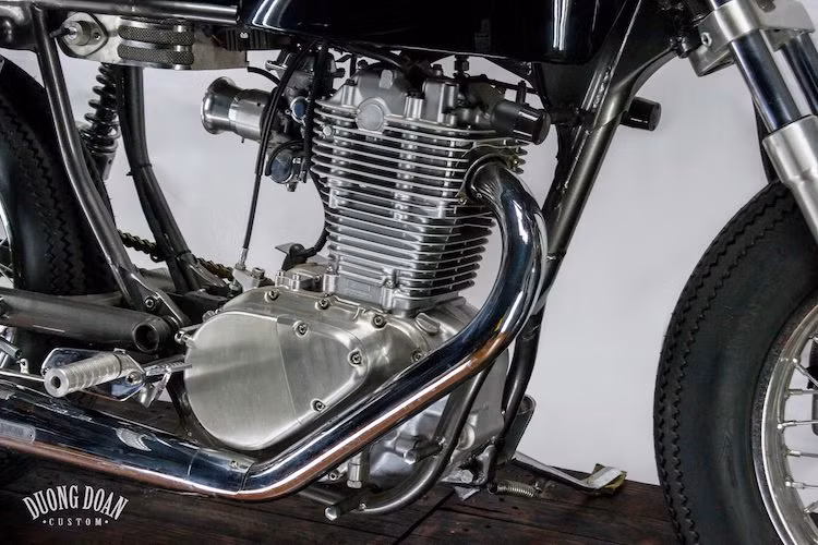 Hệ thống xaả của chiếc xe cũng là "hàng thửa" với cổ pô và pô đều do DuongDoan chế tạo. Trên bản độ này, cấu trúc khung của Savage 400 đã được xưởng độ sửa đổi lại khá nhiều ở phía sau, tạo ra một khoảng trống ở chính giữa xe để hướng điểm nhấn vào động cơ. Nằm bên dưới yên là hộp ắc quy nhỏ gọn, với các dây điện được giấu kín.