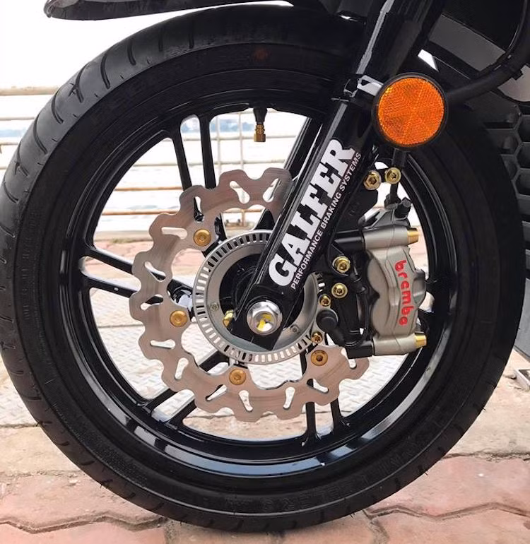 Ở phía trước, hệ thống phanh của SH300i đã được nâng cấp khá "khủng" với đĩa Galfer và heo Brembo M50 vốn dành cho môtô phân khối lớn, được bắt vào xe qua pad nhôm CNC nhuộm đen. Do vòng cảm biến bên trong đĩa được giữ nguyên nên hệ thống ABS của SH300i vẫn làm việc bình thường sau khi phanh trước được độ lại.