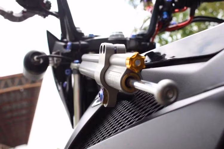 Được gắn ở sườn xe, cây trợ lực Ohlins kèm pad nhôm giúp cho chiếc xe máy côn tay Satria FU150 FI ổn định hơn khi chạy ở tốc độ cao. Ngoài ra, trợ lực này cũng có thể điều chỉnh được độ nặng nhẹ.