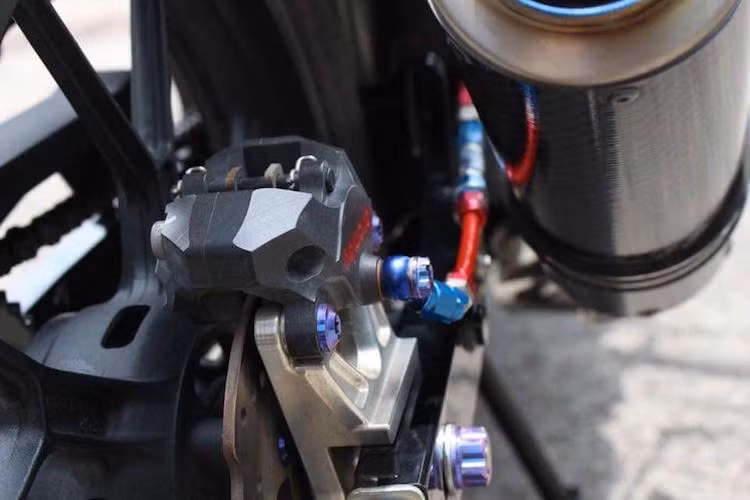 Giống như phía trước, phía sau chiếc Satria cũng được nâng cấp hệ thống phanh nguyên bản bằng heo Brembo Billet HP đối xứng 2 pis, kết hợp cùng với dây dầu Earl's. Để gắn được heo dầu vào xe, người thợ đã phải "thửa riêng" pad nhôm CNC.