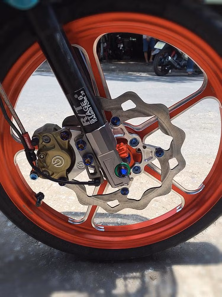 Trên bản độ này, chi tiết nổi bật nhất phải kể tới bộ mâm Racing Boy 5 cây CNC màu cam nổi bật, với trị giá lên tới khoảng 20 triệu đồng. Ngoài ra, "dàn chân" trước của chiếc xe còn được độ lại vỏ phuộc Stage 6, heo Brembo 2 pis, đĩa Galfer lòng CNC và dàn ốc trang trí titan.