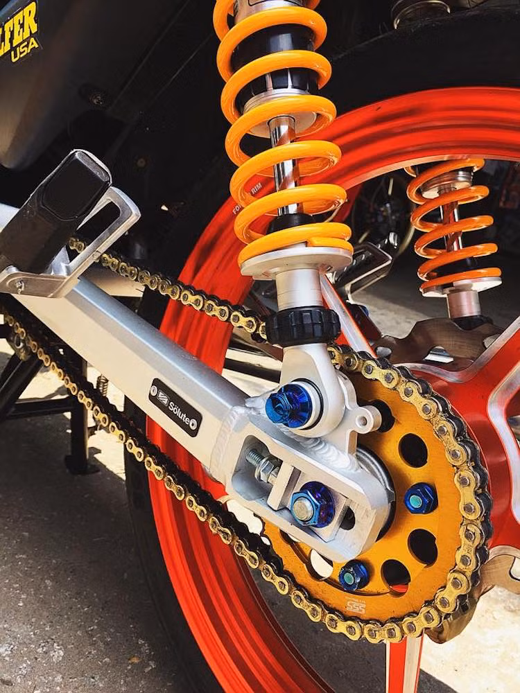 Với bộ gắp nhôm Solute, phía sau chiếc Wave không chỉ sắc sảo mà còn ổn định và nhẹ hơn gắp zin nguyên bản. Ngoài ra, xe còn được trang bị cặp phuộc Ohlins đắt giá, cùng với nhông sên đĩa SSS.