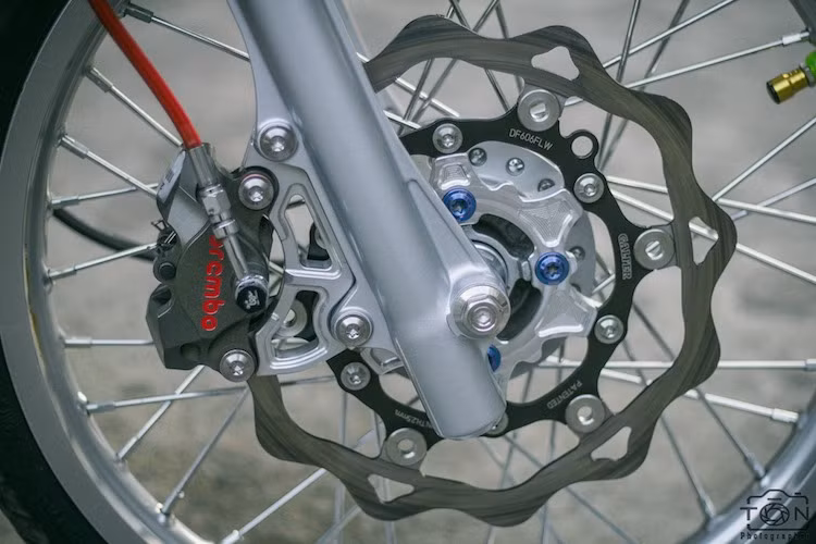 Ở phía trước, hệ thống phanh đĩa nguyên bản của xe đã được nâng cấp với đĩa Galfer lòng nhôm CNC, đi kèm với heo dầu Brembo Billet 2 pis đối xứng đẳng cấp. Vốn có bánh căm nguyên bản, chiếc Wave Thái đã được chủ xe độ cặp niềng nhôm Excel bản trước/sau 1.6 và 1.85 inch sắc sảo, nổi bật hơn.