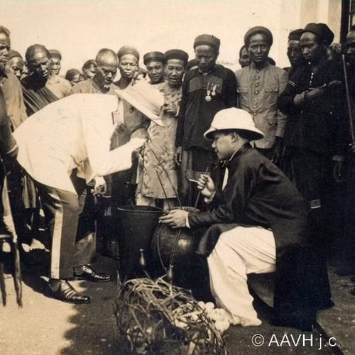 Vua Bảo Đại (mặc áo dài sẫm màu) nếm rượu cần theo phong tục địa phương ở Pleiku.