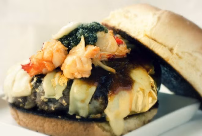 Bánh mì kẹp thịt “Douche Burger” - 666 USD (New York, Mỹ): Chiếc bánh đắt đỏ này gồm các thành phần là thịt bò Kobe nhồi gan ngỗng, phủ phô mai Gruyere, trứng cá muối, nấm Truffle, tôm hùm và rưới một loại nước sốt đặc biệt làm từ hạt cà phê chồn và bọc trong giấy tráng vàng.
