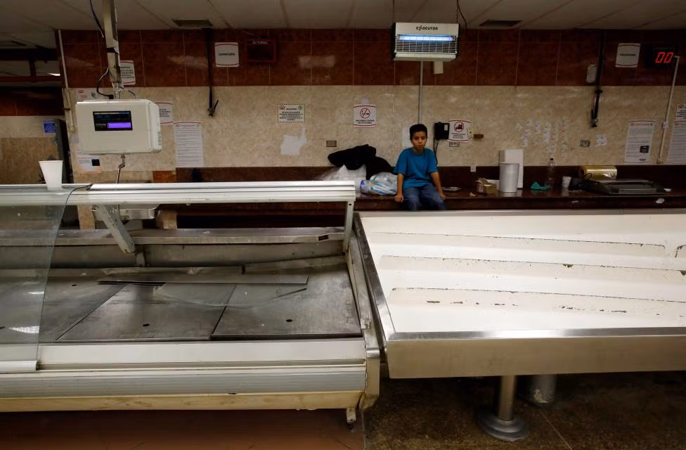 Cậu bé ngồi cạnh gian hàng thực phẩm đông lạnh đã trống trơn.