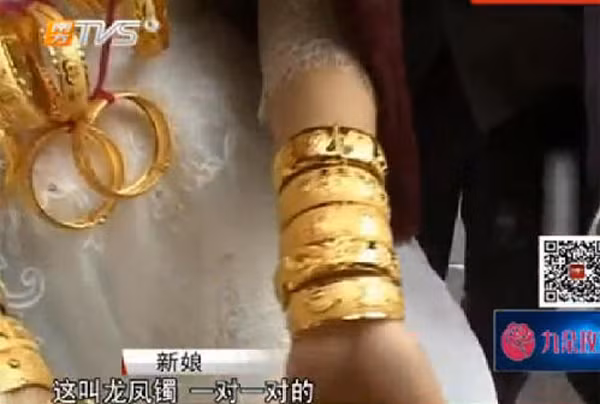 Hai bên tay cô dâu đeo đầy vòng vàng, được người đẹp tiết lộ đó là vòng long phượng, phải đeo cân xứng số lượng hai bên tay. Được biết, khối lượng vàng cô dâu này đeo trong ngày cưới nặng gần 10kg, tính giá giá trị lên đến 1,4 triệu NDT (4,7 tỉ đồng).
