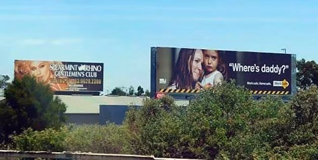 Tấm biển “Hãy đến với câu lạc bộ đêm của chúng tôi" trong khi đó, bên cạnh là biển quảng cáo "Bố đâu rồi hả mẹ?".