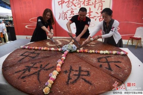 Chiếc bánh nướng khổng lồ có đường kính rộng hơn 2,4m, nhân jambon, phía trên trang trí hoa tươi cùng dòng chữ "Trung thu vui vẻ!" được rắc bằng bột chocolate, thu hút sự chú ý của rất nhiều người.