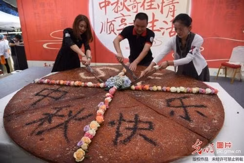 Chiếc bánh nướng khổng lồ có đường kính rộng hơn 2,4m, nhân jambon, phía trên trang trí hoa tươi cùng dòng chữ "Trung thu vui vẻ!" được rắc bằng bột chocolate, thu hút sự chú ý của rất nhiều người.