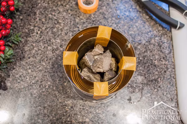 Đầu tiên, bạn lồng hai lon thiếc (một chiếc lon lớn và một lon nhỏ hơn) vào nhau. Dùng băng dính cố định hai chiếc lon rồi đổ nước ngập một nửa chừng giữa khe rỗng giữa hai lon.