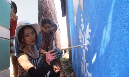 Họa sĩ Oh Ye Seul đang hoàn tác bức tranh người tuyết trên tường nhà dân Tam Thanh. Ảnh: H.Văn.