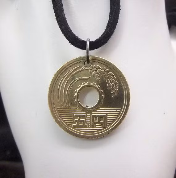 Ở mặt trước của đồng tiền là các yếu tố kinh tế đầu ngành của Nhật Bản: cành lúa đại diện cho lâm nghiệp, thủy sản và nông nghiệp, bánh răng xung quanh các lỗ đại diện cho công nghiệp. Về phía đuôi cũng là một cặp mầm mà được cho là tượng trưng cho sự tăng trưởng của Nhật thành một quốc gia dân chủ.