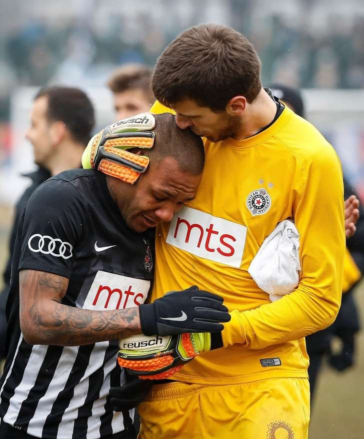 Một thủ môn đang an ủi đồng đội của mình trước sự chỉ trích nặng nề từ phía các cổ động viên quá khích.