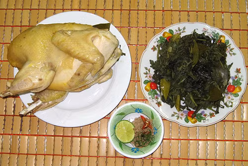 Tiếp đó lấy một chiếc xoong vừa đủ chứa con gà, sau đó dùng giấy bạc lót đáy xoong để khi hấp không bị cháy. Sau khi lót giấy bạc đó rải đều gói muối xuống dưới đáy xoong. Bạn hãy tiếp tục rải thêm vài nhánh sả sau đó là 1 lớp rau ngải cứu và đặt gà lên trên.