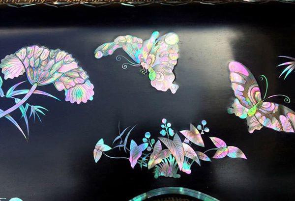 Bức tranh thiên nhiên có hoa, bướm, cỏ cây trên cánh tủ khảm trai.