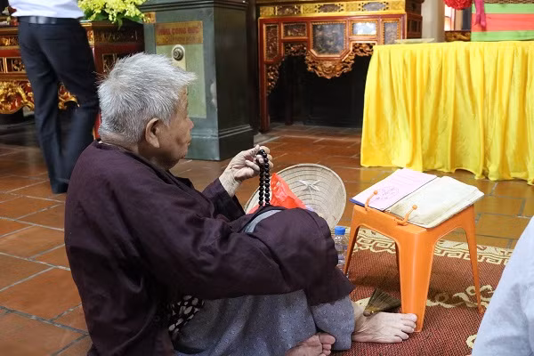 Một cụ bà đang chăm chú đọc kinh cầu siêu.