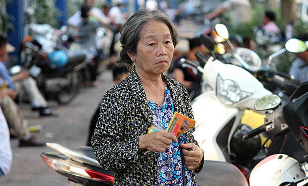 Thời tiết nắng nóng, khó chịu các phụ huynh đưa con cháu mình đi thi tạm dùng tờ rơi để làm quạt mát.