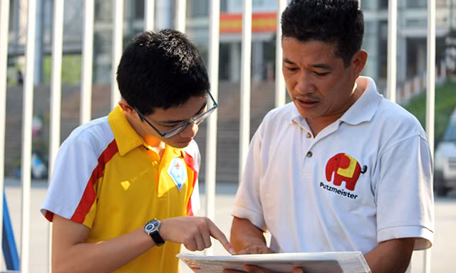 Ghi nhận của PV Kiến Thức tại điểm thi trường THPT chuyên Hà Nội - Amsterdam (Hoàng Minh Giám, phường Trung Hòa, quận Cầu Giấy, Hà Nội), mặc dù 9h mới bắt đầu làm thủ tục và phổ biến quy chế thi nhưng các thí sinh được phụ huynh đưa đến từ rất sớm. Trong ảnh, thí sinh Lê Đặng Thành (THCS Tây Sơn) được bố nhắc nhở kiểm tra lại thông tin trước khi vào làm thủ tục...