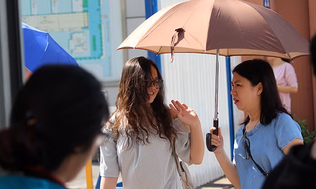 Một bậc phụ huynh vừa đi vừa che ô đưa con gái vào tận cổng trường thi.