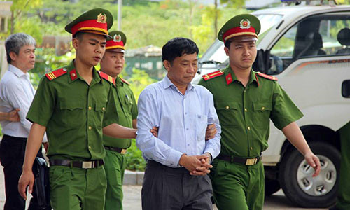 Bị cáo Ninh Văn Quỳnh (đi trước) và bị cáo Nguyễn Xuân Sơn (sau) được cảnh sát dẫn giải đến tòa.