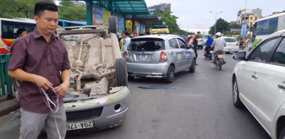 Sau khi đâm vào hàng rào chắn ở điểm trung chuyển xe buýt, ô tô con lao vào xe taxi rồi lật chổng vó trên đường.