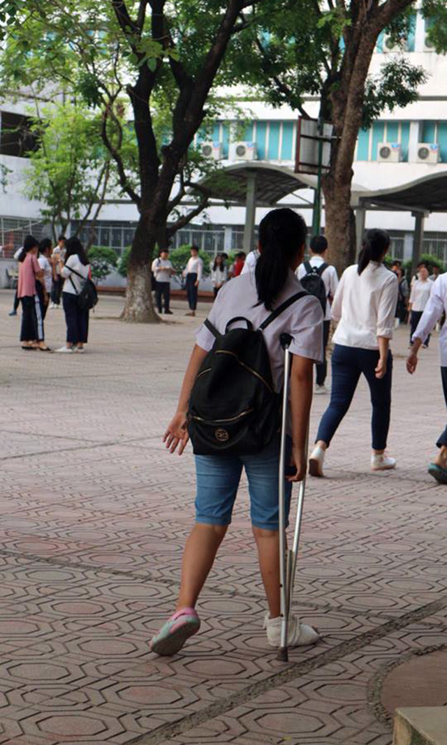 Hình ảnh một thí sinh nữ bị chấn thương ở chân phải, nhưng vẫn cố gắng chống nạng tới điểm thi trường Nguyễn Trãi - Ba Đình.