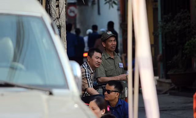 Các bậc phụ huynh kiên nhẫn ngồi đợi con ở ngoài điểm thi trường THPT Yên Hòa trong thời tiết nắng nóng.