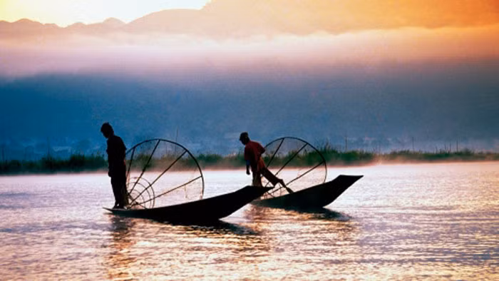 Bóng người đánh cá tung lưới trên hồ nước ngọt Inle, Myanmar lúc bình minh.