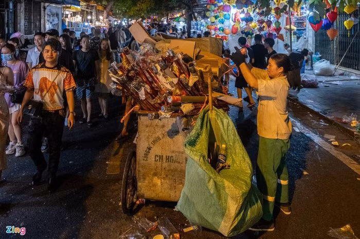 Chiếc xe đẩy chất đầy túi nylon, cốc nhựa dùng một lần, pháo giấy. Chị Nhung cho biết ngay từ 18h nhiều nơi trên phố đã xuất hiện rác.
