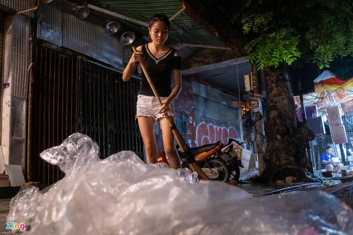 Chị Thanh, nhân viên bán hàng tại phố Hàng Mã dọn vỉa hè sau khi đóng cửa nghỉ. "Tôi chất gọn lại cho công nhân quét rác tiện thu gom. Tất cả vì ý thức giữ gìn vệ sinh chung", chị nói.