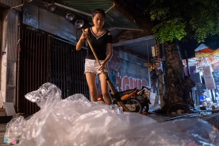 Chị Thanh, nhân viên bán hàng tại phố Hàng Mã dọn vỉa hè sau khi đóng cửa nghỉ. "Tôi chất gọn lại cho công nhân quét rác tiện thu gom. Tất cả vì ý thức giữ gìn vệ sinh chung", chị nói.
