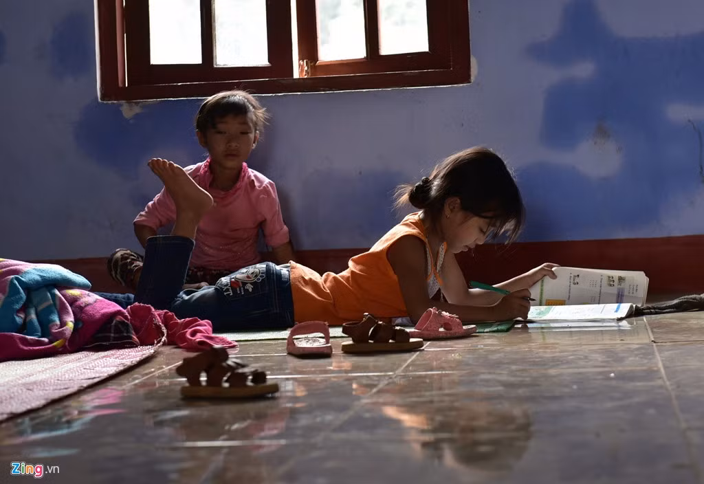 Bé Trương Thị Ngà (7 tuổi), học sinh trường Tiểu học Tân Hóa không thể đi học nên tự làm bài khi nằm trên sàn tầng 3 của chính ngôi trường đang theo học.