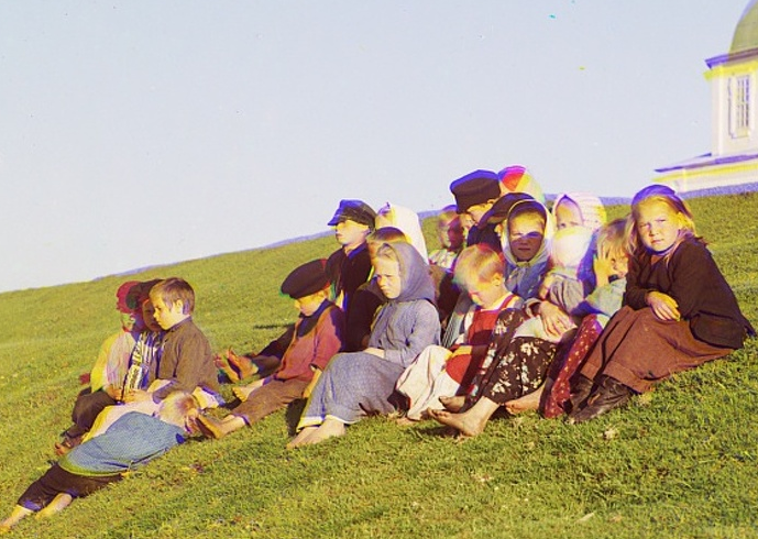 Một nhóm trẻ em ngồi trên bãi cỏ trong bức ảnh màu chụp tại Đế quốc Nga hơn 100 năm trước.