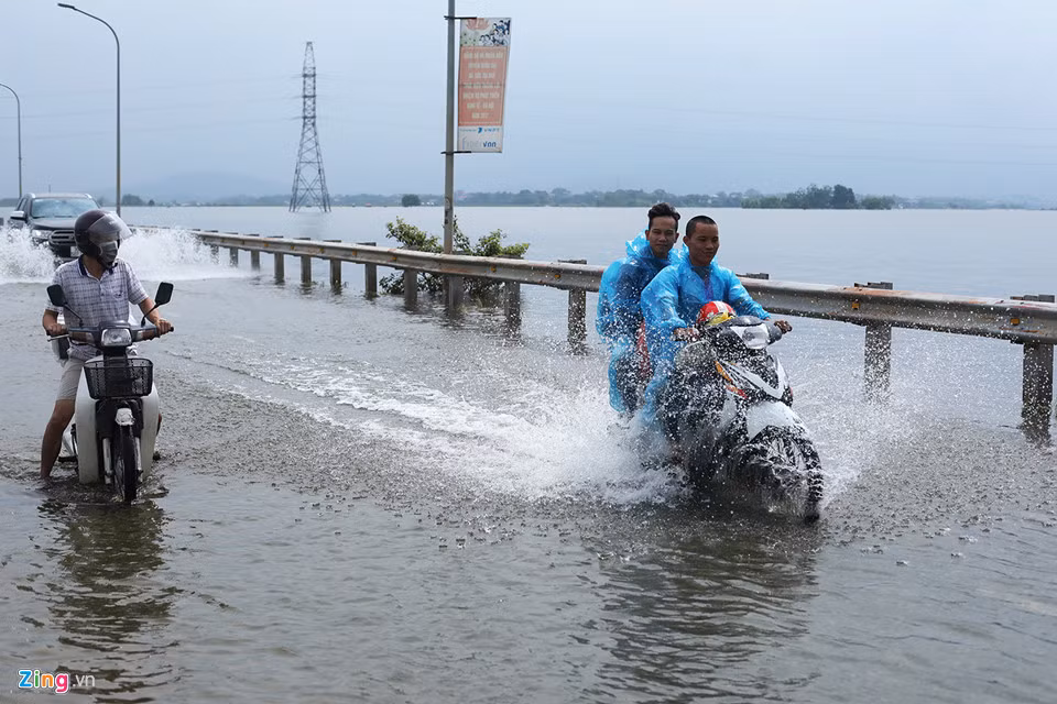 Nhiều người đi xe máy lảo đảo trước những làn sóng nước do ôtô tạo ra.