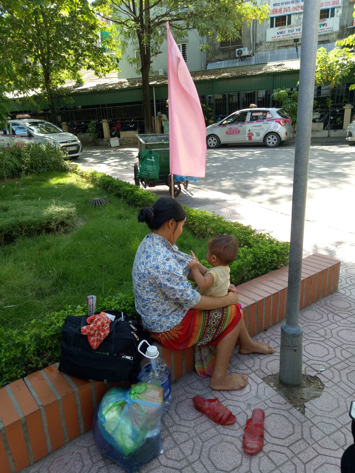 Hai mẹ con người dân tộc Dao (Ba Vì, Hà Nội) vừa xuống đến viện Nhi, tìm ngay chỗ râm ngoài trời để ngồi chờ vì trong khu khám bệnh theo bảo hiểm đông bệnh nhân, nóng nực.