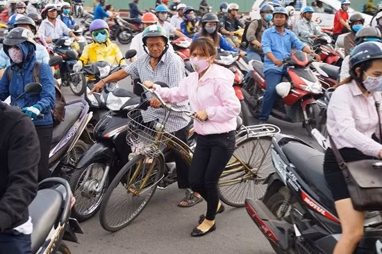 Đường kẹt cứng, cô gái dẫn bộ xe đạp luồn lách khỏi cảnh ùn tắc.