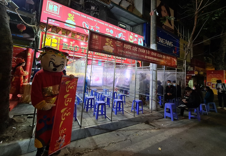 Để đảm bảo an toàn cho khách hàng đến giao dịch trước tình hình dịch bệnh COVID-19 diễn biến phức tạp, Bảo Tín Minh Châu ở Trần Nhân Tông đã dựng vách ngăn mica trong suốt trước cửa cho khách xếp hàng khi chờ giao dịch.