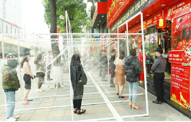 Khách hàng đứng giãn cách theo vị trí được đánh dấu trong vách mica khi đến giao dịch ở Bảo Tín Mạnh Hải.