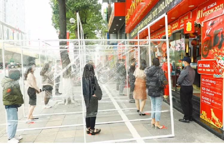 Khách hàng đứng giãn cách theo vị trí được đánh dấu trong vách mica khi đến giao dịch ở Bảo Tín Mạnh Hải.