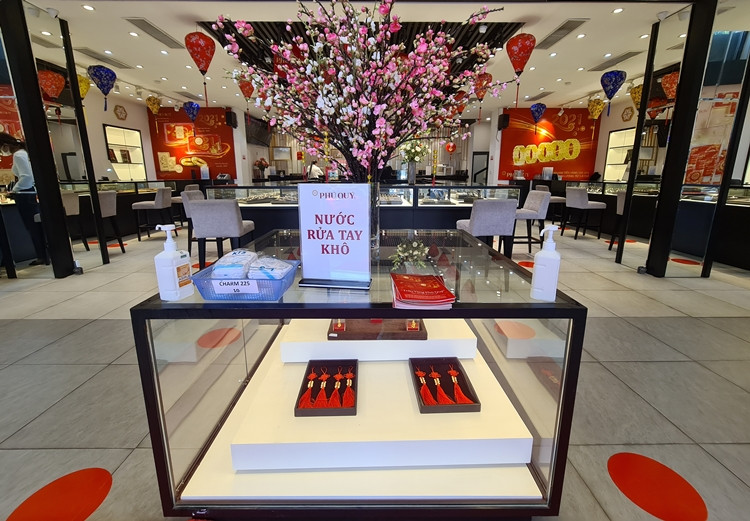 Tương tự, cửa hàng vàng của Vàng bạc Phú Quý nằm trên đường Cầu Giấy (Hà Nội) cũng chuẩn bị nước rửa tay khô, khẩu trang đặt ở ngay cửa ra vào. Bên trong cửa hàng còn dán các dấu đỏ thể hiện vị trí đứng giãn cách cho khách đến giao dịch.