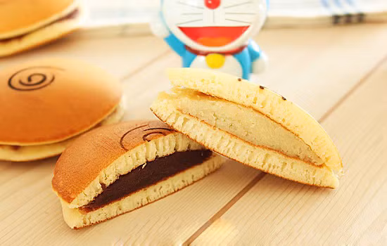 Bánh rán Doraemon nhân đậu đen. Để làm món ăn này các mẹ cần có lò nướng trong nhà và hơi tốn công một chút vì phần vỏ bánh và ruột được làm riêng sau đó mới kẹp với nhau. Các mẹ có thể điều chỉnh lượng đường trong nhân tùy theo ý thích của bé.