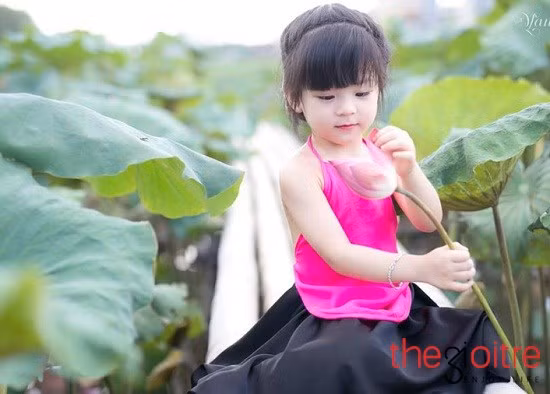 Một em bé rất xinh mặc áo yếm ngồi giữa đầm sen. Ảnh: Thegioitre.