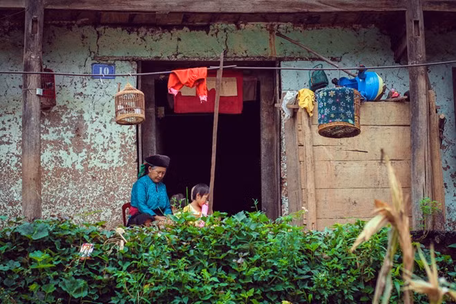 Em bé cùng bà ngồi chơi bên hiên nhà. Ảnh: Baodatviet.