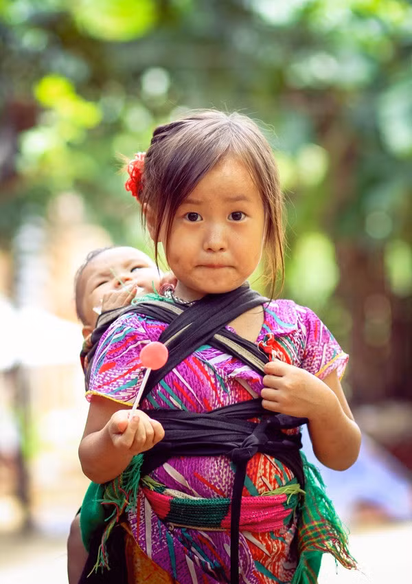 Một cô bé ở Hà Giang địu đứa em trên lưng. Ảnh: Baodatviet.