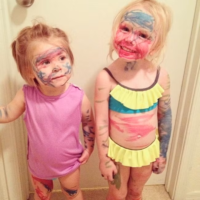 Hai chị em nở "nụ cười chiến thắng" sau khi nghịch ngợm tô vẽ chán lên người nhau. Ảnh: Brightside.