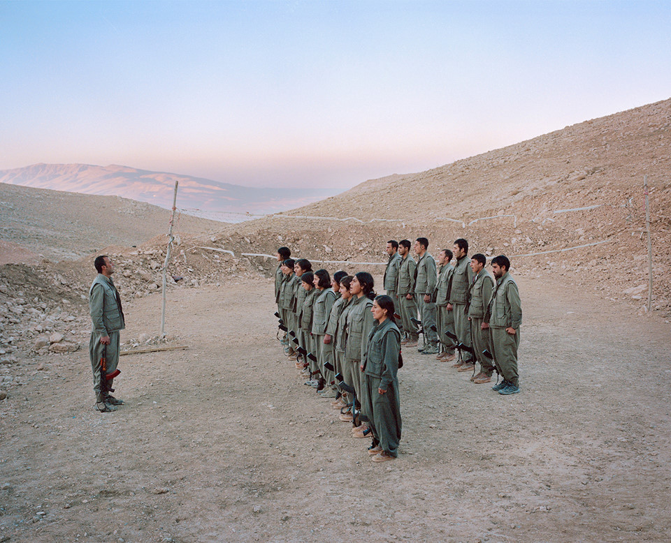 Hơn 10.000 người tị nạn người Kurd đã trốn khỏi Thổ Nhĩ Kỳ vào những năm 1990 khi ngôi làng của họ bị lực lượng chính phủ đốt cháy và đang sống trong trại tị nạn Makhmur ở miền Bắc Iraq. Sau khi trại bị IS tấn công vào năm 2014, các chiến binh du kích đã đóng quân quanh các ngọn đồi xung quanh để bảo vệ. Đàn ông và phụ nữ sống trong các trại tách biệt nhưng thường tập luyện cùng nhau và chiến đấu kề vai sát cánh.